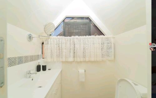 uma casa de banho com uma janela, um lavatório e um WC. em Snow-white's 2 bedroom City heart Cottage in Perth 6000 em Perth