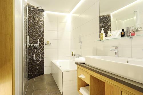 a white bathroom with a sink and a shower at Alpenhotel Ischglerhof in Ischgl