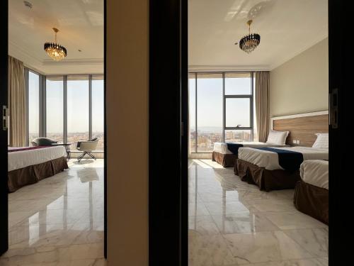 a hotel room with two beds and a large window at Taiba Karim Hotel Madina in Al Madinah