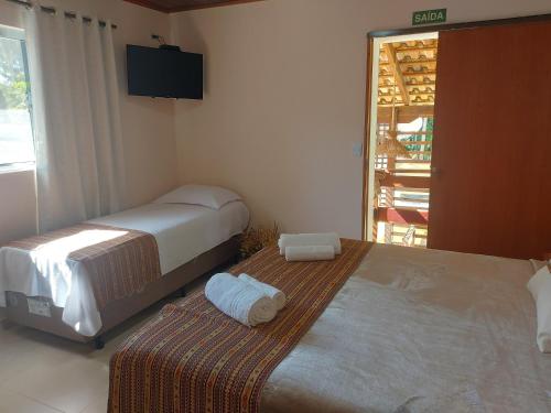 a bedroom with two beds and a television on the wall at Pousada Ninhal das Garças in Ilha Comprida
