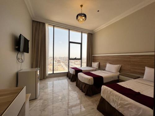 a hotel room with two beds and a large window at Taiba Karim Hotel Madina in Al Madinah