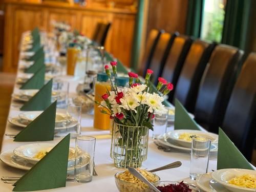 a long table with plates and a vase of flowers at Hotel i Restauracja Castle in Bystrzyca Kłodzka