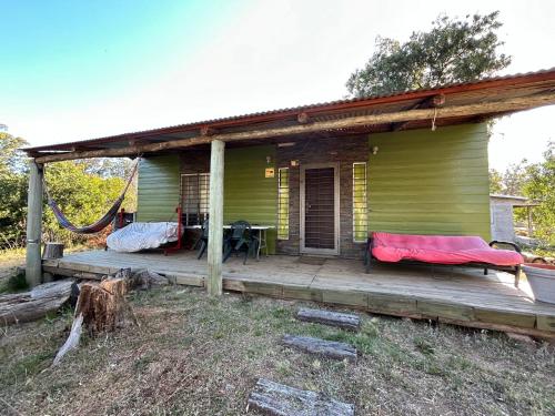 ein grünes Haus mit einer Veranda mit einer Hängematte darauf in der Unterkunft Gran escape! Santa Ana in Cuchilla Alta