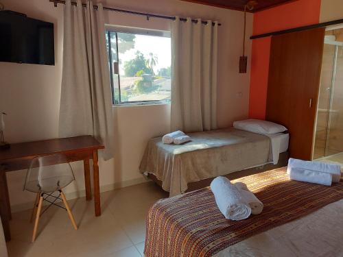 a small room with two beds and a window at Pousada Ninhal das Garças in Ilha Comprida