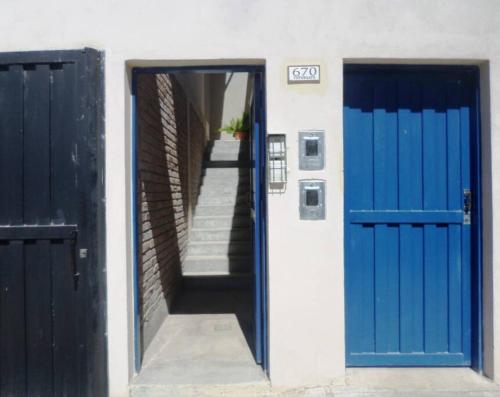 two blue doors on a white building with stairs at Departamento confortable en Guaymallén in Guaymallen