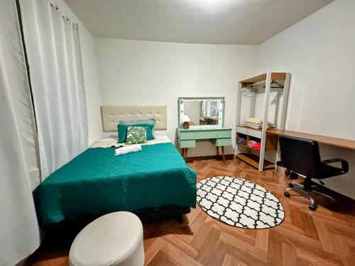 Espaço Nill في بيلو هوريزونتي: غرفة نوم بسرير اخضر ومكتب