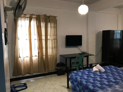 Schlafzimmer mit einem Bett, einem Schreibtisch und einem TV in der Unterkunft Aladino Hostel in Dasmariñas