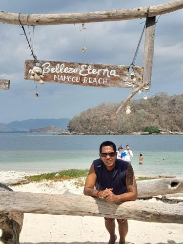 a man sitting on a fence at the beach at Kubu Pilatus – Family House Lombok in Tjakranegara