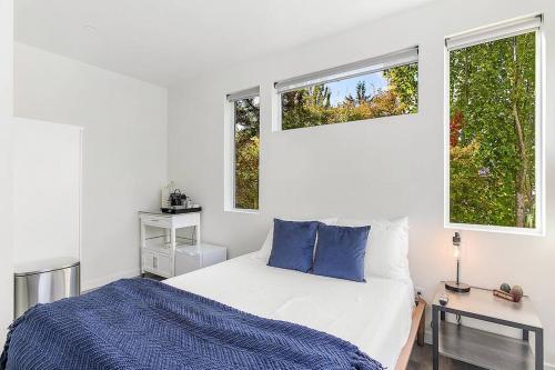 a white bedroom with a bed and two windows at Syrax's Dragonstone Den in Seattle