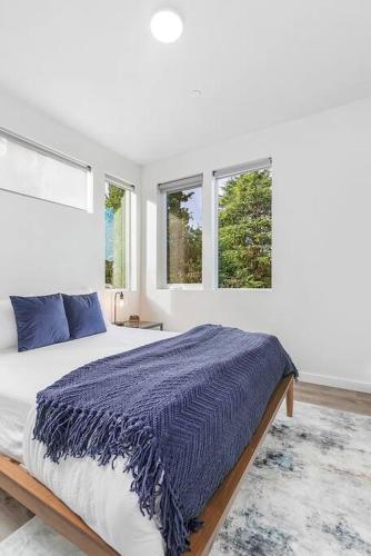 a bedroom with a bed with a blue comforter and two windows at Syrax's Dragonstone Den in Seattle