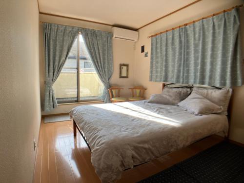1 dormitorio con cama y ventana grande en 4 Bedrooms, 3 Toilets, 2 bathtubs, 2 car parking , 140 Square meter big Entire house close to Makuhari messe , Disneyland, Airports and Tokyo for 18 guests, en Narashino
