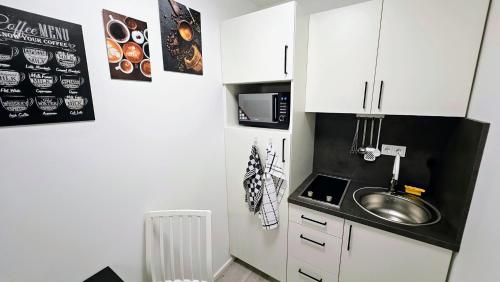 una pequeña cocina con fregadero y microondas en Apartment Küche Arbeitsplatz Netflix WLan Barrierefrei en Augsburg