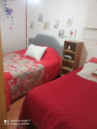 two beds in a room with red sheets at Hostal¤ Familiar¤ in Chillán