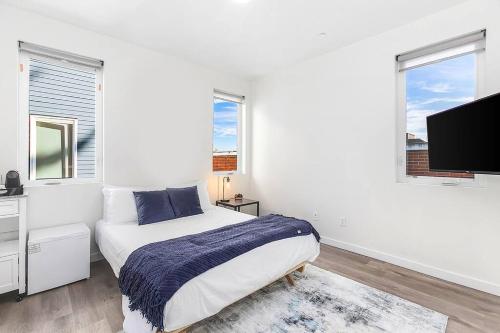 a white bedroom with a bed and a flat screen tv at Caraxes's Blood Wyrm Lair in Seattle