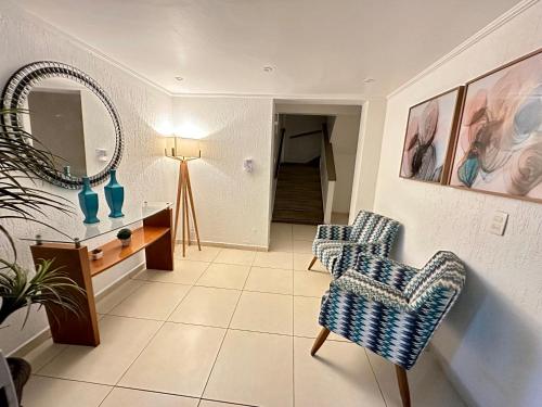 sala de estar con 2 sillas y espejo en Apartamento Américo Vespúcio, en Cabo Frío