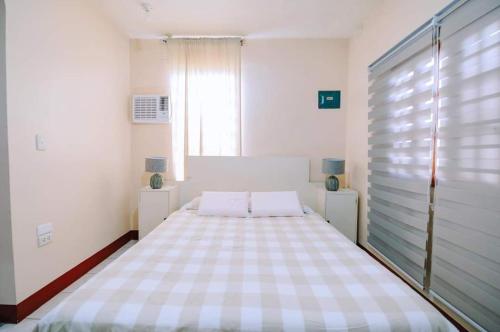 1 dormitorio blanco con 1 cama grande y ventana en Malibu Homes, en Casisang