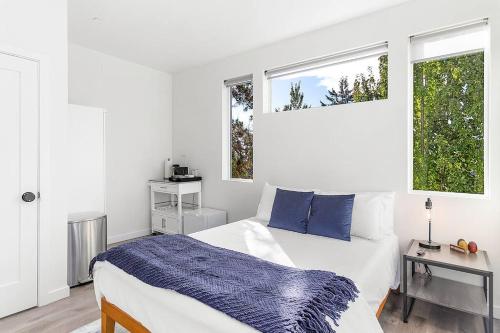 a white bedroom with a bed and two windows at Vhagar's Valyria's Vista in Seattle