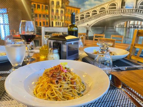 a plate of pasta on a table with wine glasses at Hotel Vista del Cerro in Fortuna