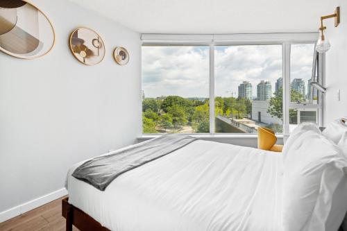 1 dormitorio con cama blanca y ventana grande en GardenView Modern Condo with Parking, Gym, Pool, AC en Vancouver