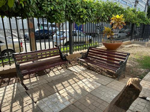 two wooden benches sitting next to a fence at Casa Los Almendros , Casa Completa Valledupar in Valledupar