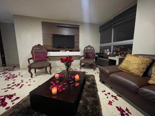 Five Stars Suites - Kennedy - Guayaquil في غواياكيل: غرفة معيشة مع أريكة وطاولة مع زهور