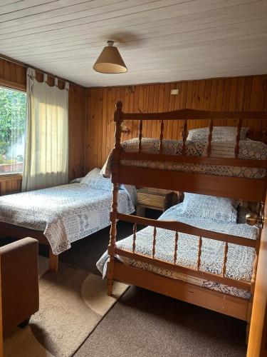 a bedroom with two bunk beds and a window at Hostal y Cabañas Villa Germana in Puerto Varas