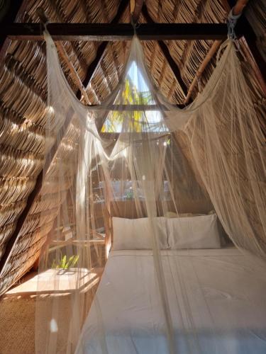 uma cama num quarto com telhado de palha e uma janela em Ecocamping Lumiar em Amontada