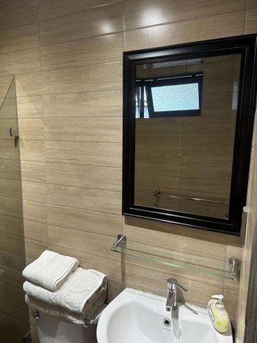 y baño con lavabo, espejo y aseo. en Hostal y Cabañas Villa Germana, en Puerto Varas