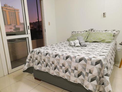 1 dormitorio con 1 cama con edredón gris y blanco en Central APTO Santa Cruz do Sul en Santa Cruz do Sul