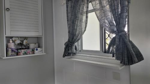a window with a checkered curtain in a bathroom at Hidden Gem Holiday Let in South Mission Beach