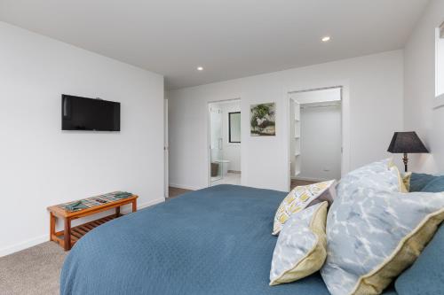 a bedroom with a blue bed and a television at Pembroke Heights in Moeraki
