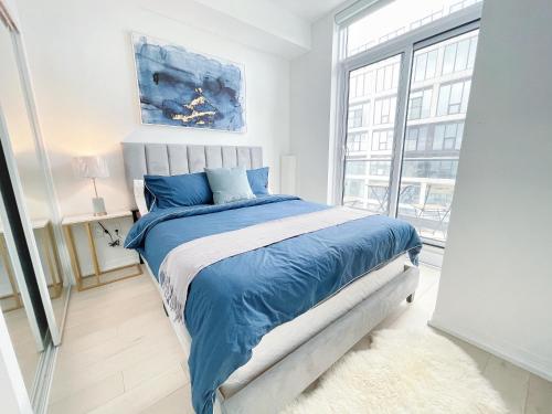 um quarto com uma cama com lençóis azuis e uma janela em INFIVILLA Amazing Penthouse Living in Sunrise- Breathtaking Skyline Lake View Downtown Toronto!A em Toronto