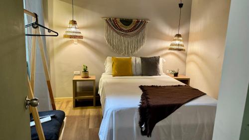 a bedroom with a bed and two pendant lights at Luum Guest House in Medellín