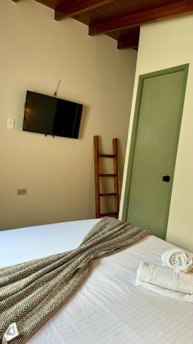 a bedroom with a bed with a flat screen tv on the wall at Luum Casa Hotel Manila in Medellín