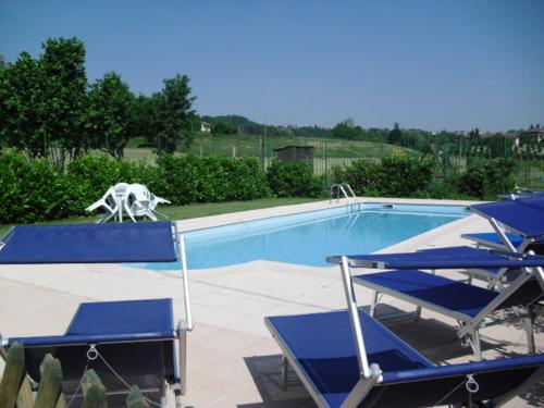 a pool with blue chairs and a statue of a horse at Agriturismo Isorella in Cherasco