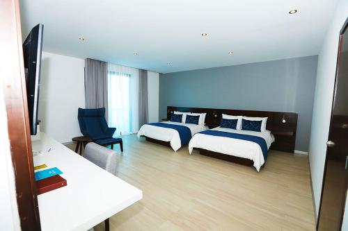 una habitación de hotel con 2 camas y una silla en Hotel Marea Vista en Ensenada