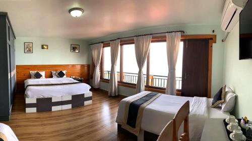 a hotel room with two beds and a balcony at The Lapsi Tree in Nagarkot