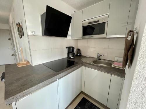 une petite cuisine avec un évier et un micro-ondes dans l'établissement Appartement T2 cabine avec climatisation, parking privatif à Sète - FR-1-338-466, à Sète