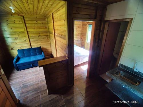 Habitación con sofá azul en una cabaña de madera en Chalés Maravilha 01, en Alfredo Chaves