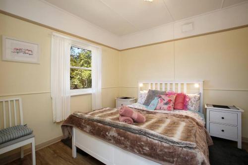 um quarto com uma cama com almofadas cor-de-rosa e uma janela em Tullys Hut em Wentworth Falls