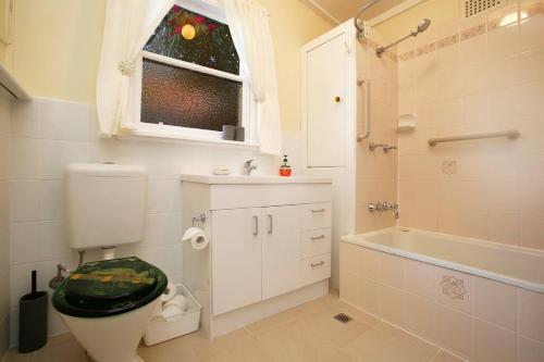 uma casa de banho com um WC, uma banheira e uma janela. em Tullys Hut em Wentworth Falls