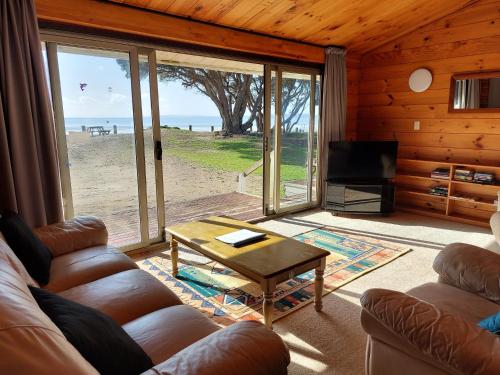 a living room with a view of the beach at Edgewater Motel in Orewa