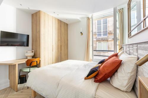 une chambre avec un lit, un bureau et une télévision dans l'établissement La Suite du Marais, à Paris