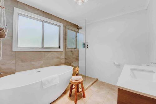 a bathroom with a white tub and a window at Whimsical Willunga Getaway in Willunga