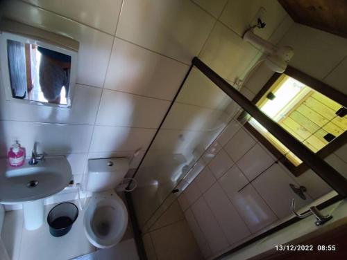 a bathroom with a toilet and a sink and a window at Chalés Maravilha 02 in Alfredo Chaves
