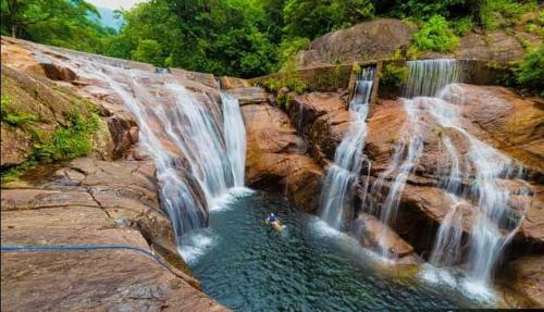 a person swimming in a pool at a waterfall at Abimansala Resort in Hunnasgiriya