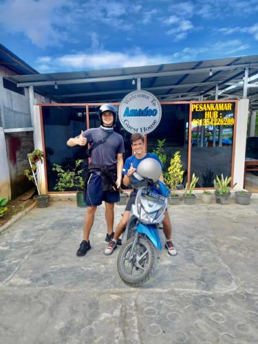 a man and a man standing next to a motorcycle at Amadeo Guest House in Ratodena