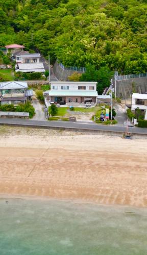 a building next to the beach and the ocean at Beach Villa Tachibana in Onomichi