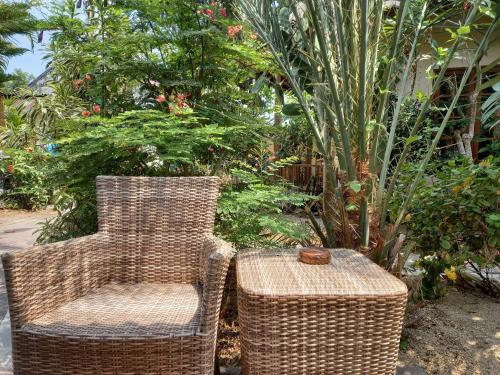 two wicker chairs and a table in a garden at Arnel Bungalows in Senggigi 