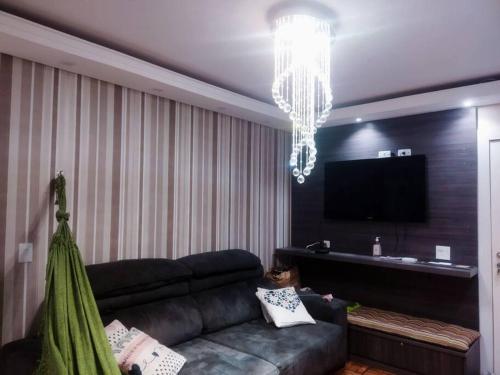 sala de estar con sofá negro y lámpara de araña en Super aconchegante Bem localizado, prox Ibirapuera, en São Paulo